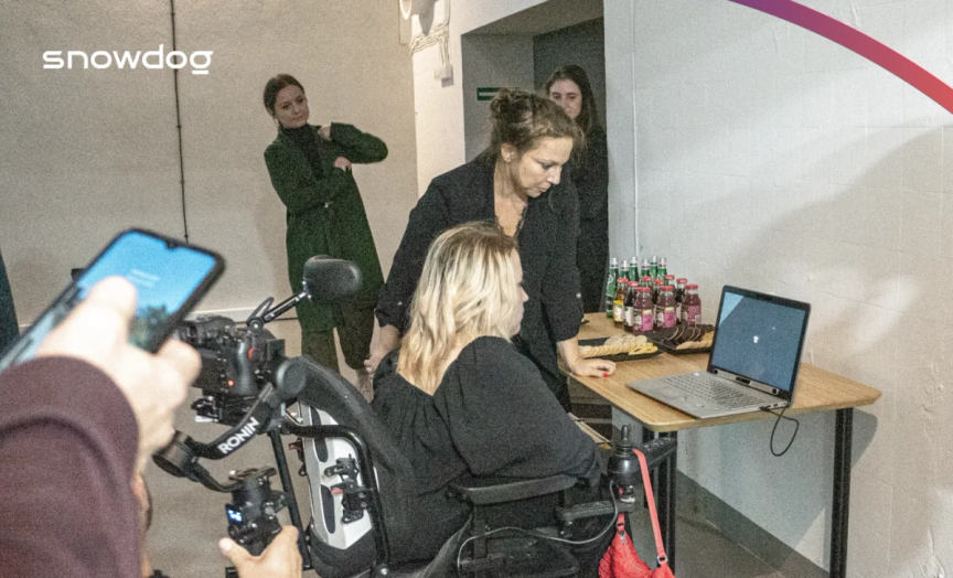 There are 4 people on this picture. Two of them are close to the desk. One is standing, the other one sitting.