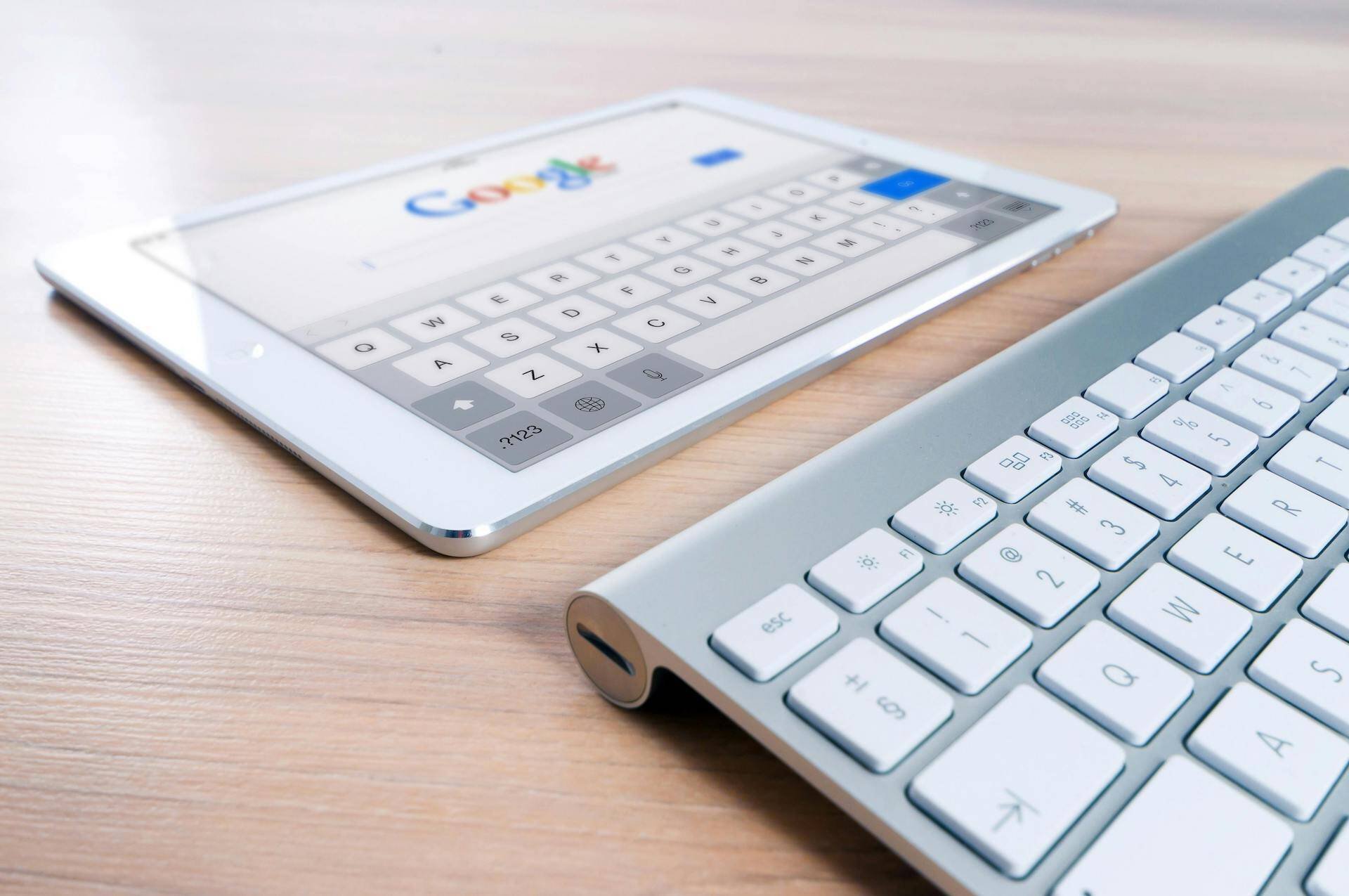 a tablet computer with the Google home page visible on screen in front of a wireless keyboard